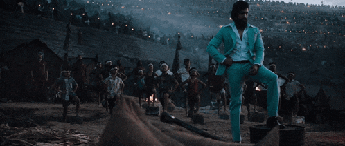 a man in a blue suit stands on a tire in front of a fire