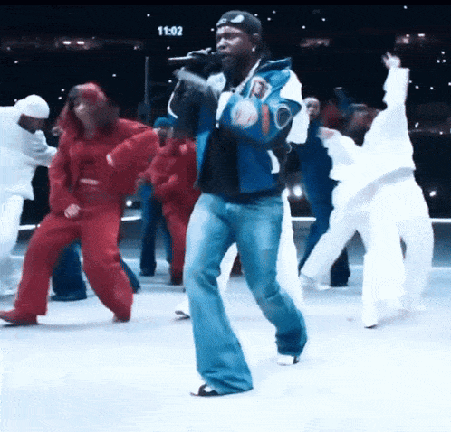a man is singing into a microphone while a group of people are dancing