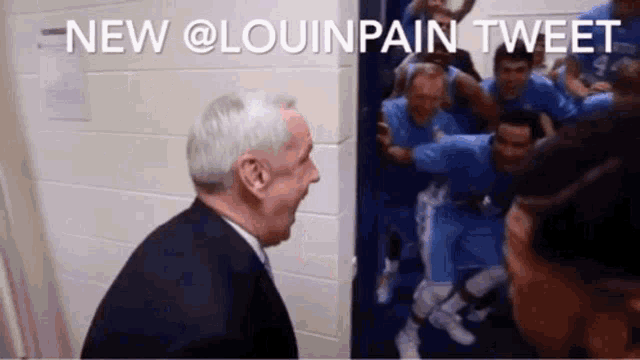 a man in a suit stands in front of a group of basketball players with the caption " new @louinpain tweet " above him