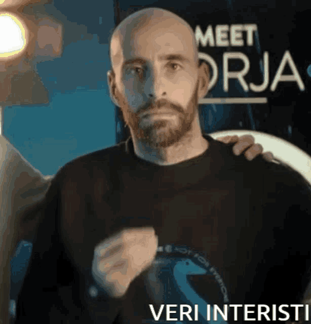 a bald man with a beard is wearing a black shirt that says " meri interisti "