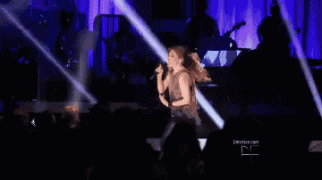 a woman singing into a microphone on stage in front of a crowd .
