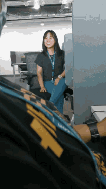 a woman wearing a lanyard with the letter t on it smiles in an office