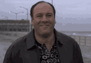 a man wearing a leather jacket and a black shirt is smiling .