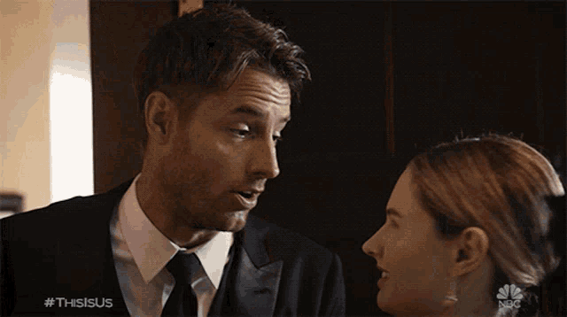 a man in a suit and tie is talking to a woman with the hashtag #thisisus