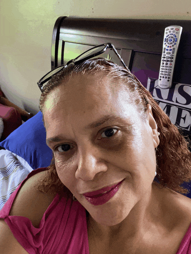a woman sitting on a bed with a remote in front of a sign that says i 'm me