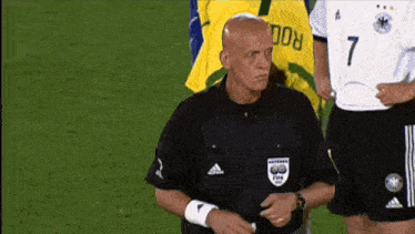 a referee stands in front of a player wearing a number 7