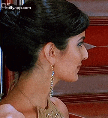 a close up of a woman 's neck and ear with a bun and earrings .