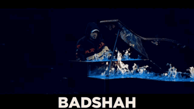 a poster for badshah shows a man playing a piano with blue flames