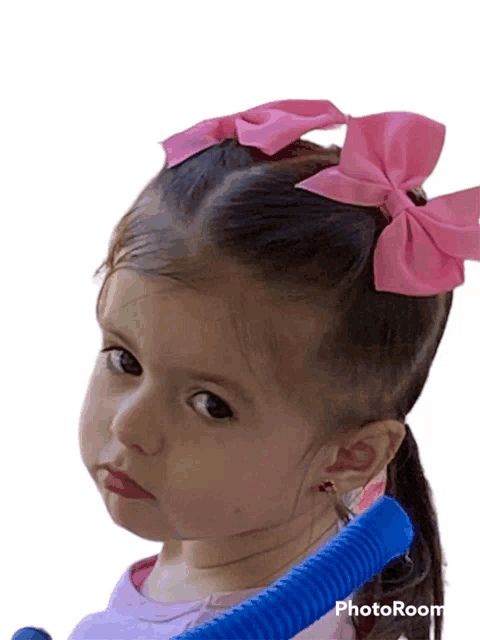 a little girl with two pink bows in her hair is holding a blue tube