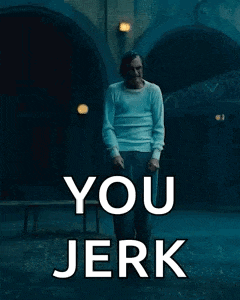 a man in a white shirt is standing in a dark room with the words `` you jerk '' written on it .