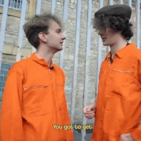 two men in orange jumpsuits are standing next to each other talking .