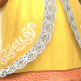 a close up of the back of a yellow dress with white lace