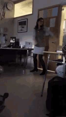 a woman is dancing in a classroom with a clock on the wall above her