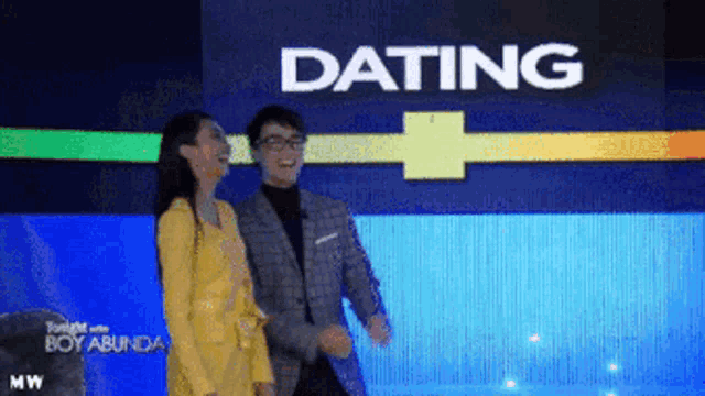 a man and a woman are dancing in front of a screen that says dating