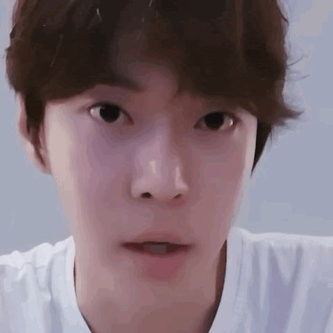 a close up of a young man 's face with a white shirt on making a funny face .