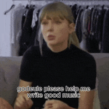 taylor swift is sitting on a couch and talking to someone while wearing a black shirt .