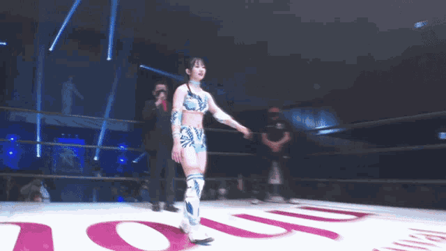 a woman in a wrestling ring stands in front of a sign that says ' oup '