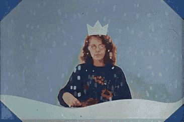 a young girl wearing a crown is standing in a snow globe .