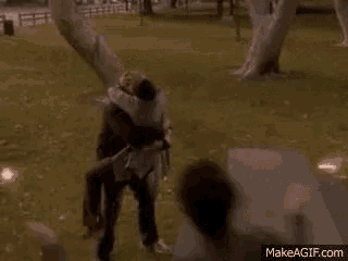 a man is carrying a woman in his arms in a field .