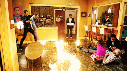 a group of people are gathered in a room with a fire coming out of the floor