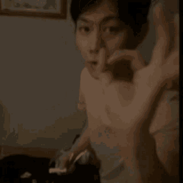 a man in a white shirt is kneeling down in a dark room with his hands in his pockets .
