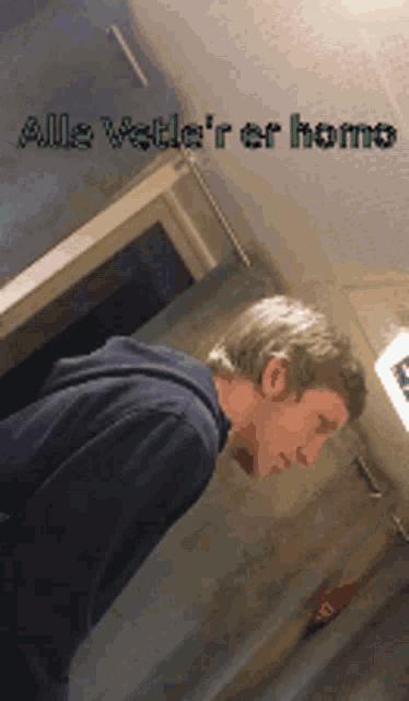 a man standing in a hallway with the words alle vette 'r er homo