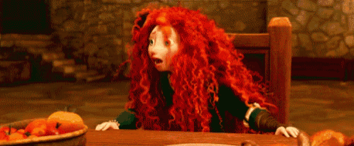 a cartoon character with red curly hair is sitting at a table .