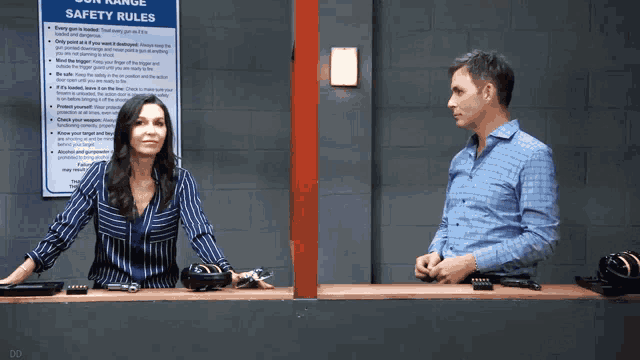 a man and a woman are standing in front of a sign that says safety rules