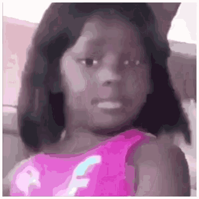 a little girl in a pink dress is making a face .