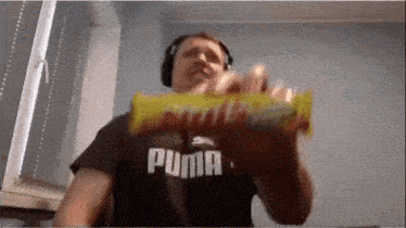 a man wearing a puma shirt is holding a candy bar in his hand