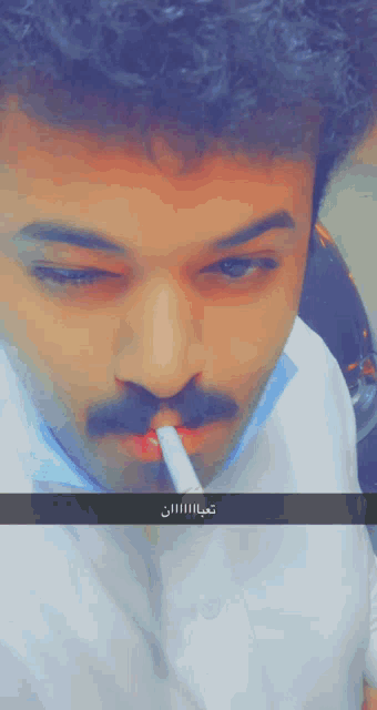 a man with a mustache is smoking a cigarette with a caption in arabic