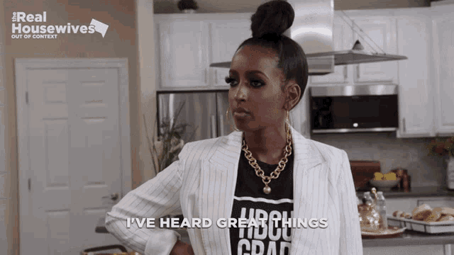 a woman wearing a black shirt that says i 've heard great things stands in a kitchen