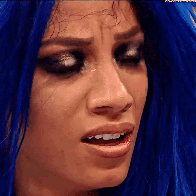 a woman with blue hair is making a funny face .