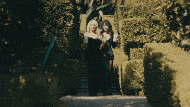 two women in black dresses are walking through a maze