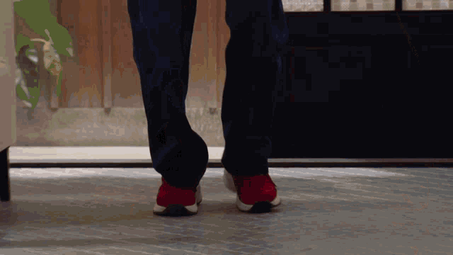 a person wearing red and white sneakers is standing on a tile floor