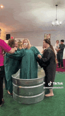 a woman in a green gown is being baptized by two other women