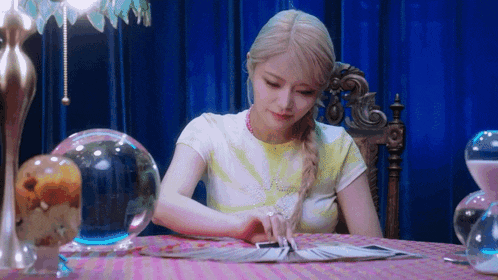 a woman is sitting at a table reading a tarot card