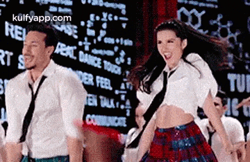 a man and a woman are dancing together on a stage in front of a large screen .