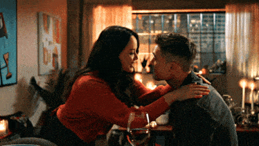 a man and woman are kissing in a living room with a glass of wine