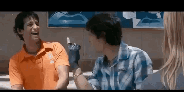 a man in an orange shirt is giving a thumbs up to another man