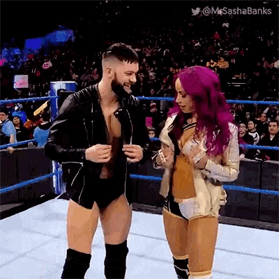 a man and a woman are standing in a wrestling ring and the woman has pink hair