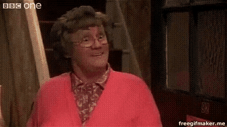 a woman in a pink sweater and glasses is smiling and looking at the camera .