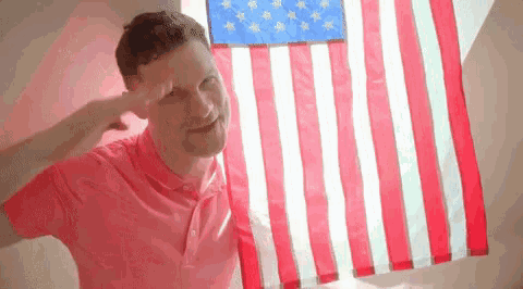a man salutes in front of an american flag .