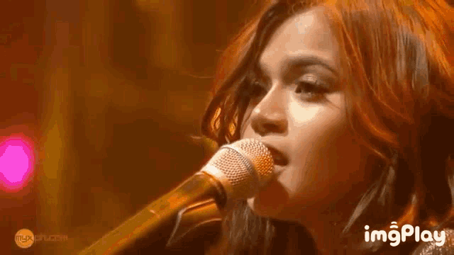 a close up of a woman singing into a microphone with the words imgplay on the bottom