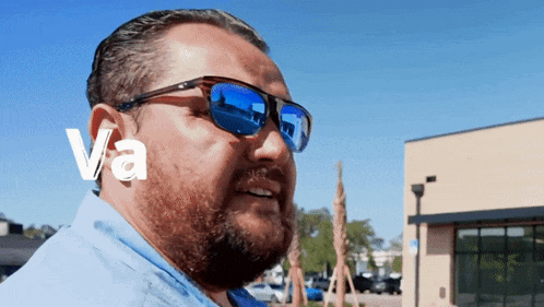 a man wearing sunglasses and a blue shirt has the word va above his head