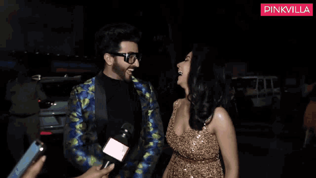 a woman in a gold dress is being interviewed by a man in a colorful suit