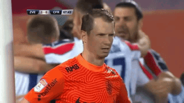 a soccer player wearing an orange jersey with the word betfair on the sleeve