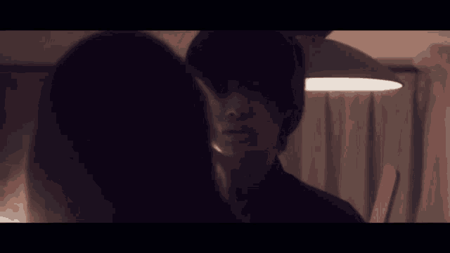 a man and a woman looking at each other in a dark room