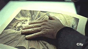 a close up of a person 's hand touching a painting .