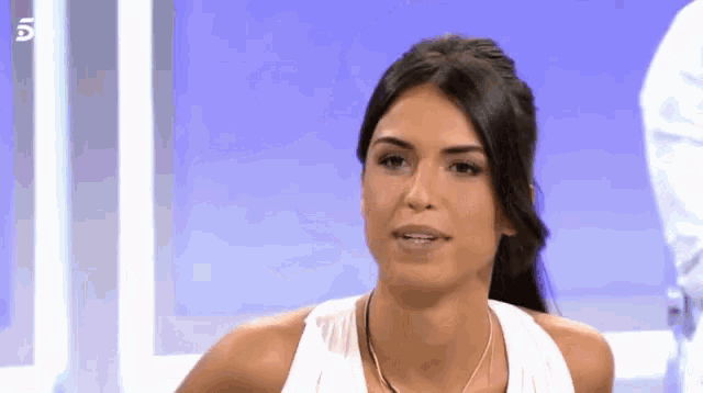 a woman wearing a white tank top and a necklace with the number 5 on the bottom right